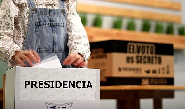 Una niña deposita su voto en una urna electoral.