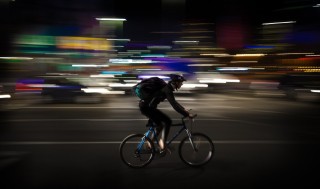 Ciclista de entrega a domicilio recorriendo la ciudad de noche