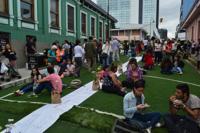 Grupos de personas sentadas sobre una gran alfombra al lado de la Alianza Francesa haciendo un pique-nique en el Festival Amón Cultural del 2018.