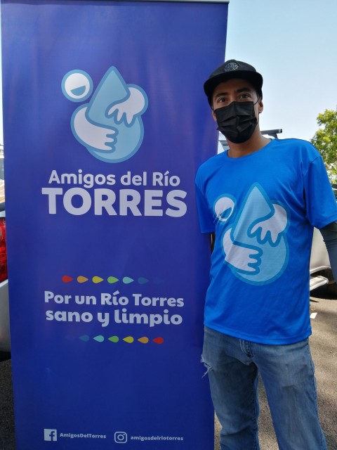 Carlos Velásquez Ortiz posa junto al banner de Amigos del Río Torres