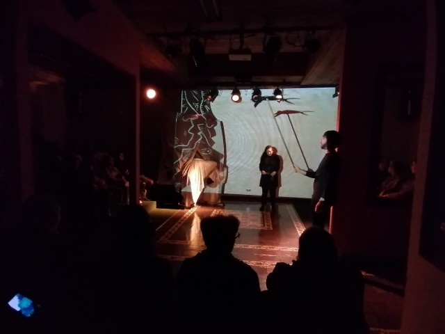 Escena de la obra donde se aprecia el grabado La niña y el viento en la proyección.