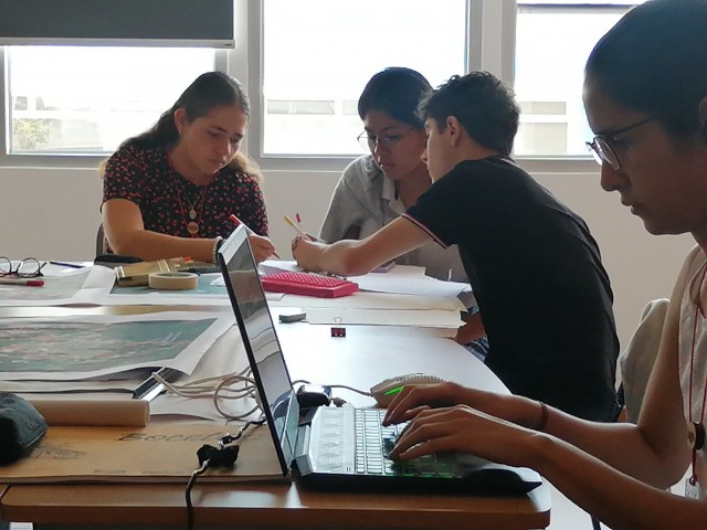 Grupo de estudiantes haciendo un trabajo en conjunto en una de las aulas de la Escuela de Arquitectura y Urbanismo.