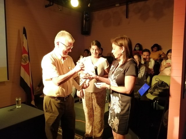 El Dr. José María Gutiérrez recibe un recuerdo de manos de Jeannette Alvarado Retana, directora de la Escuela de Arquitectura y Urbanismo. Los acompaña Mariela Hernández, coordinadora de la Unidad de Cultura y Deporte del Campus TEC San José.