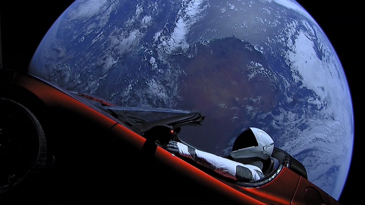 Un auto, con un manequí, en el espacio, frente a la Tierra