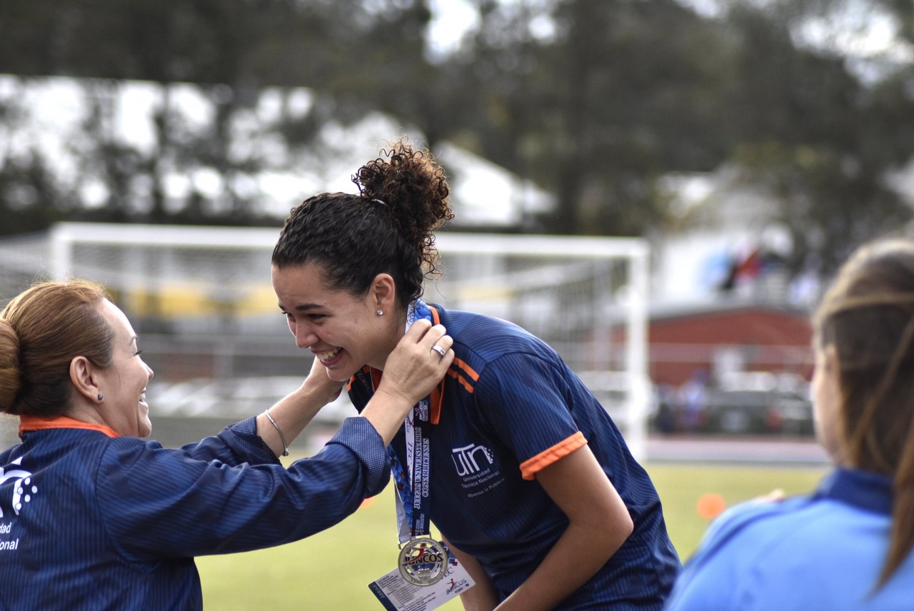 La vicerrectora coloca la medalla sobre una jugadora de la UTN.