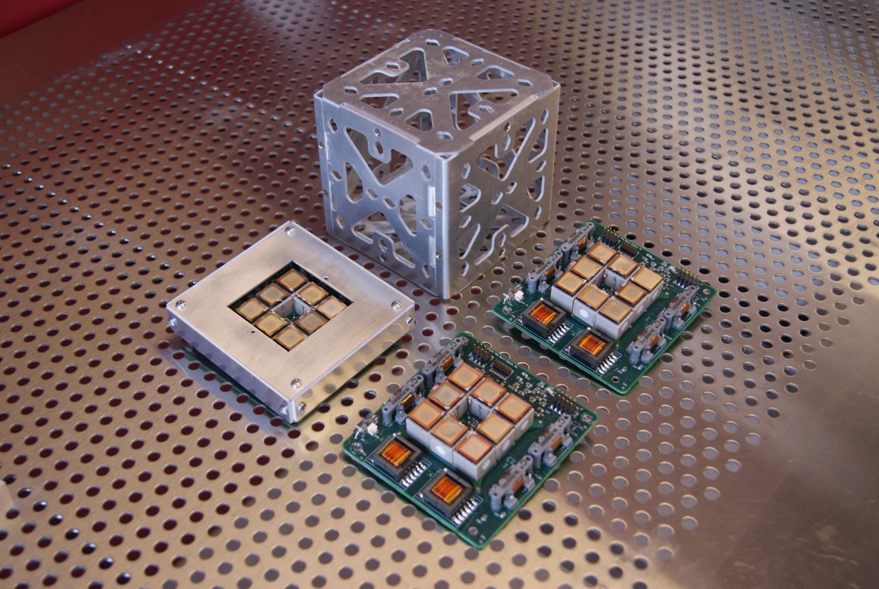 Sistema de propulsión junto a una caja de un CubeSat.