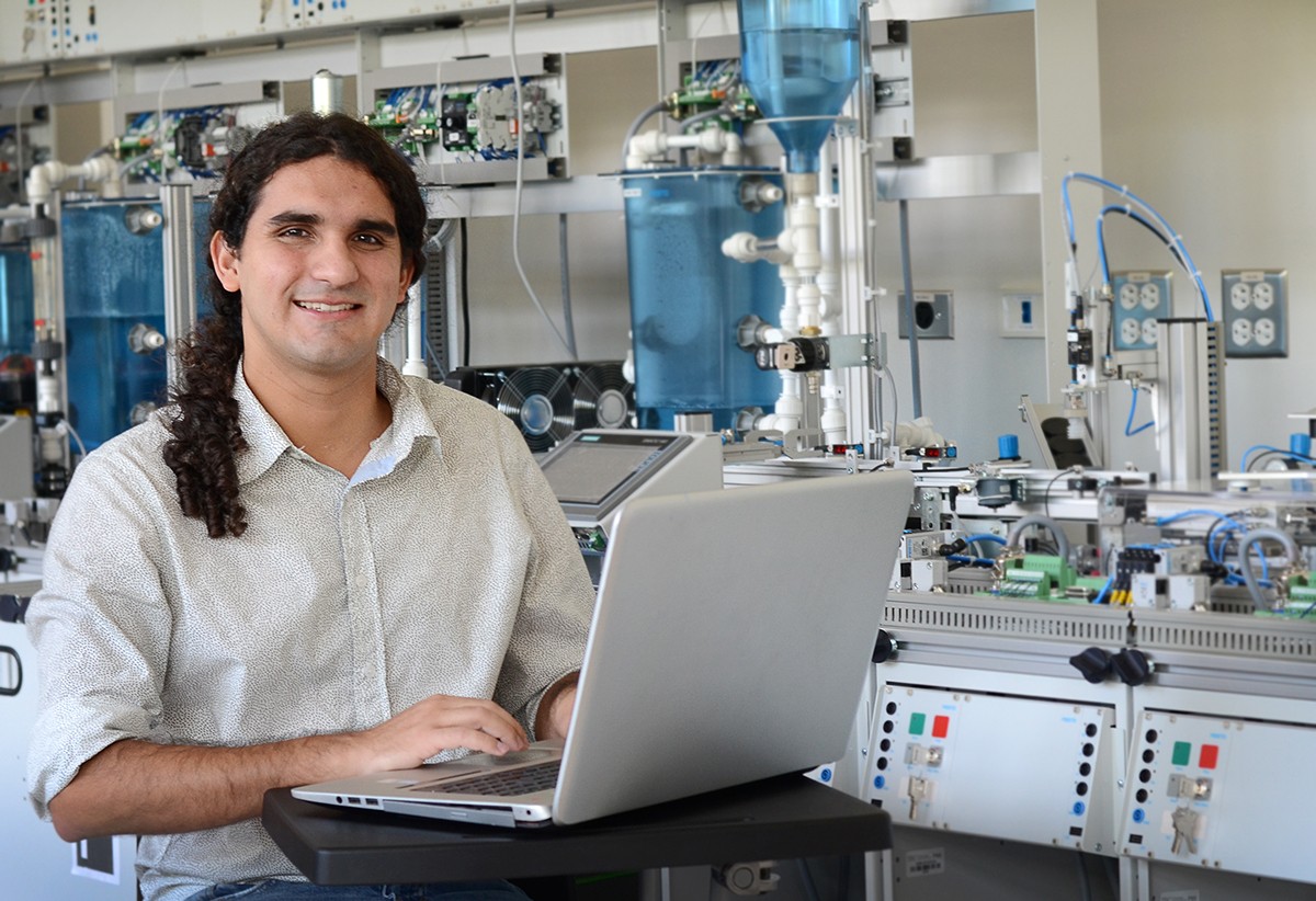 Joel sentado frente a su computadora en un laboratorio de Mecatrónica. 