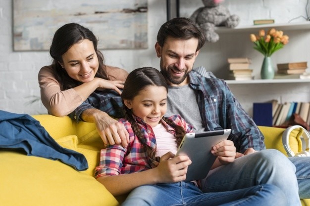 Un niño ve una tableta con sus padres. 