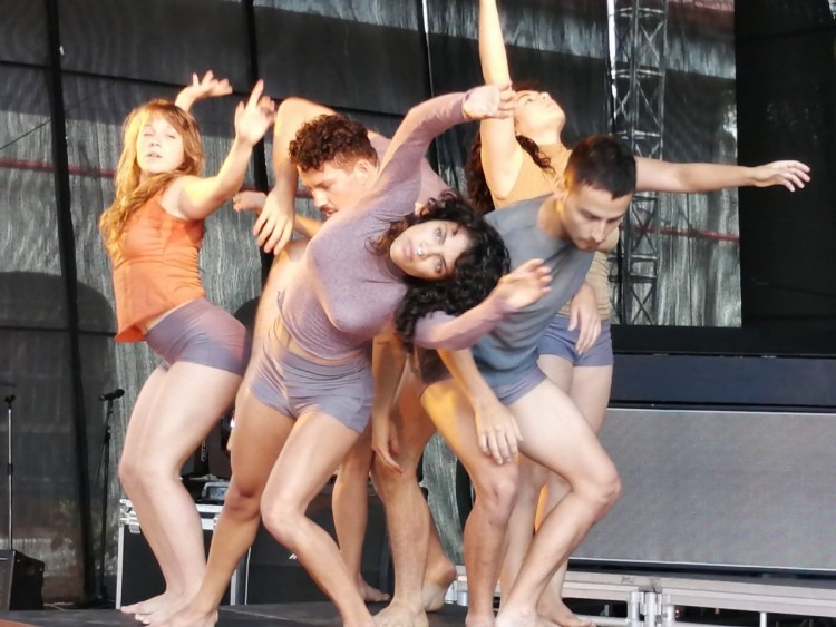 Cinco jóvenes entrecruzan sus cuerpos en un espectáculo de danza.