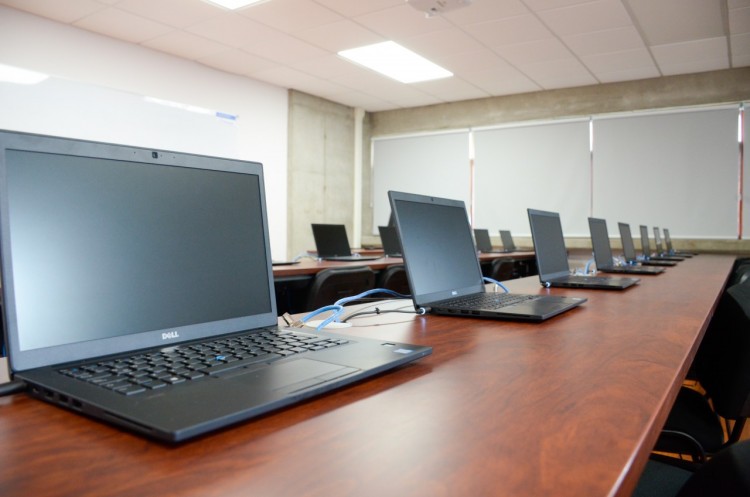 Computadoras portátiles sobre una mesa larga en un aula del edificio que ocupa la Escuela de Ingeniería en Computación