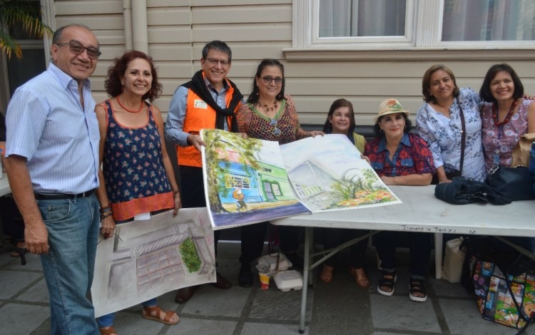 Julio César Calvo, rector del TEC (con chaleco naranja) muestra el libro gigante de pinturas del Barrio Amón creado por la agrupación Pintores al Aire Libre (Pintal). A su izquierda, Doreen Bakit, directora del grupo. Foto: Fernando Montero / OCM.