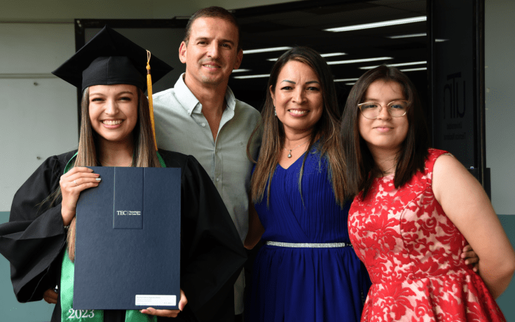 Imagen de la estudiante graduada con el título junto a sus papás y hermana.