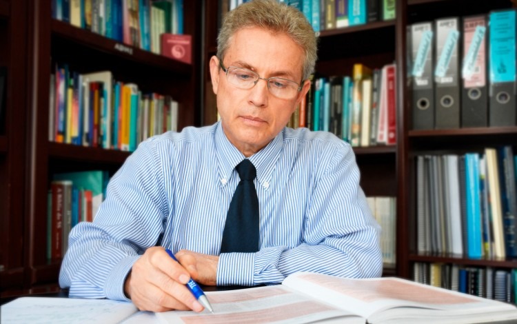 Hombre con corbata y lapicero en mano escribe en libro