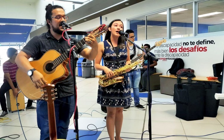 Un estudiante con guitarra y una estudiante cantando.