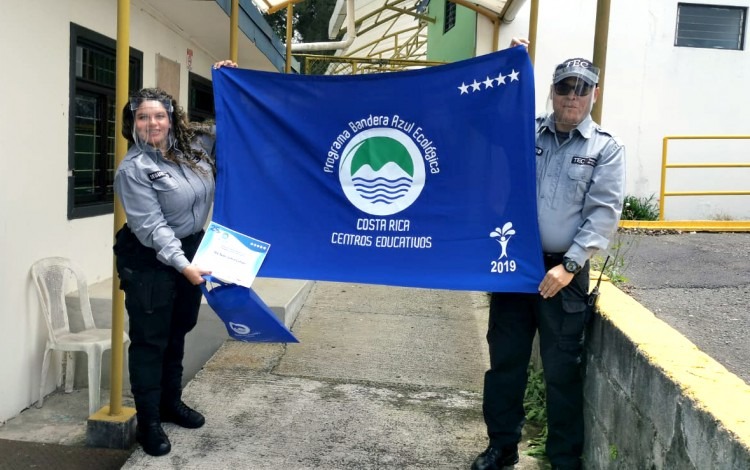 Dos guardas muestran la bandera azul del galardón.