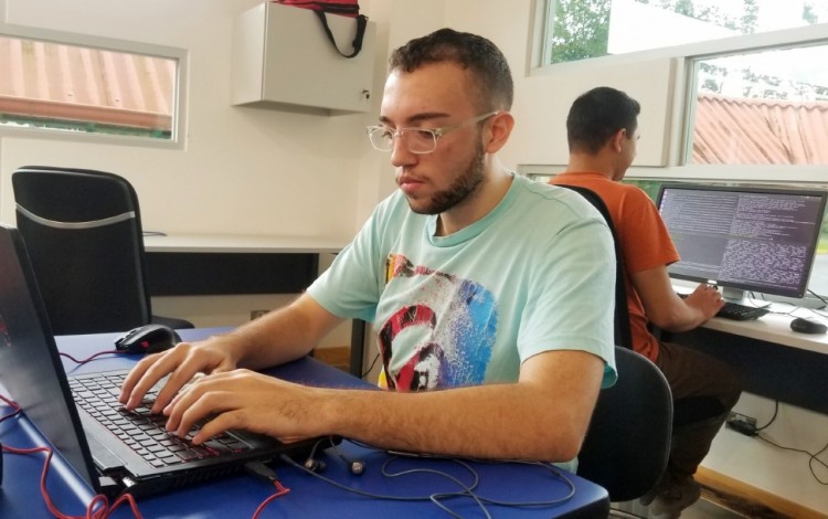 Dos estudiantes en computadoras escribiendo código.