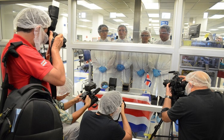 Tres fotógrafos frente a los ingenieros, separados por un vidrio. Los investigadores visten de bata de laboratorio.