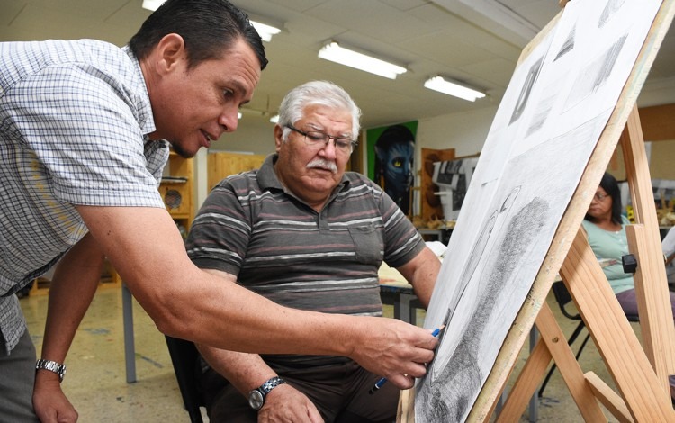 Un adulto mayor aprende a dibujar con la ayuda del profesor.