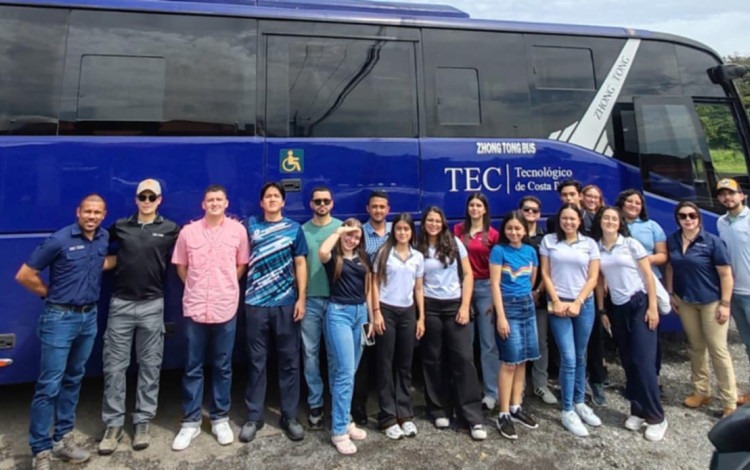 Imagen de varias personas junto a un autobus.  Las personas van rumbo a Parismina.