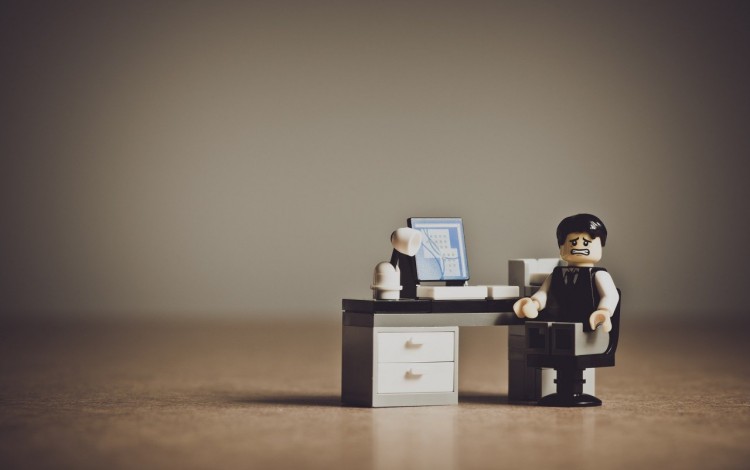 Figura de LEGO de un empresario desesperado frente a su escritorio