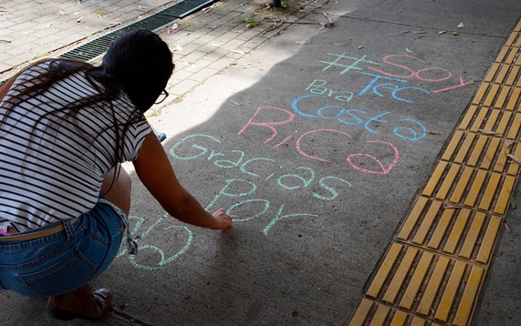 persona escribiendo en piso de pasocubierto del TEC