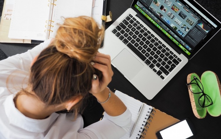 persona tomandose la cabeza frente a computadora