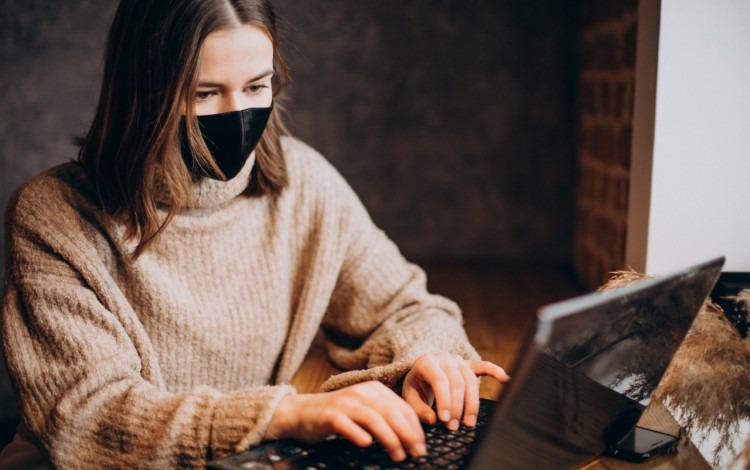 mujer con barbijo frente a computadora