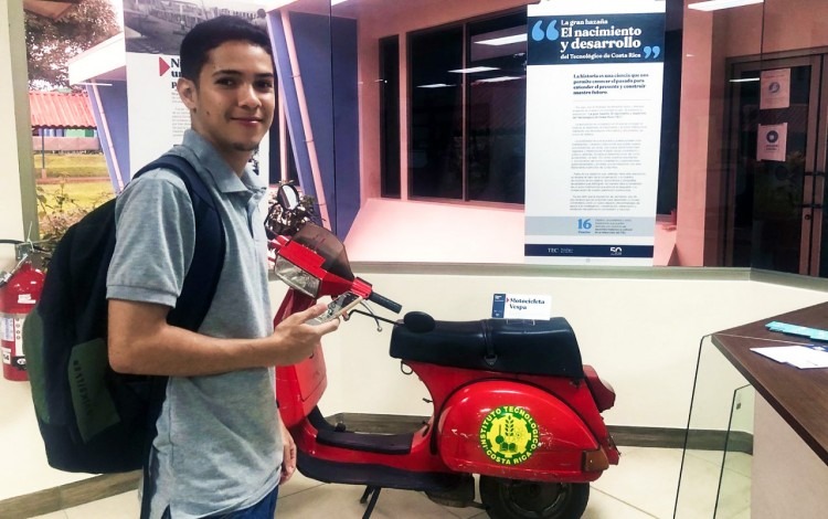 Un joven frente a la moto antigua que forma parte de la exposición