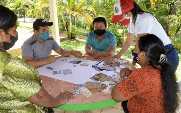 Varias personas sentadas en una mesa, con recortes de papel