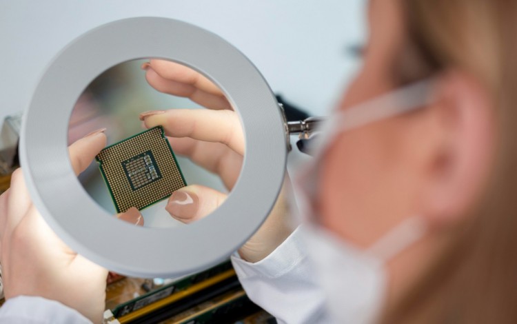 una mujer observa un semiconductor con una lupa