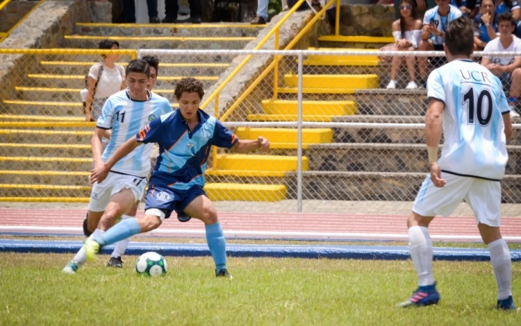 Un joven de la UTN lleva la bola mientras es marcado por un rival de la UCR.
