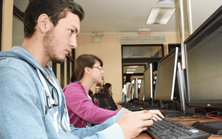 Imagen con varios estudiantes frente a la computadora.