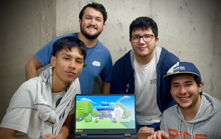 Jóvenes posan mostrando en una computadora el videjuego desarrollado. 