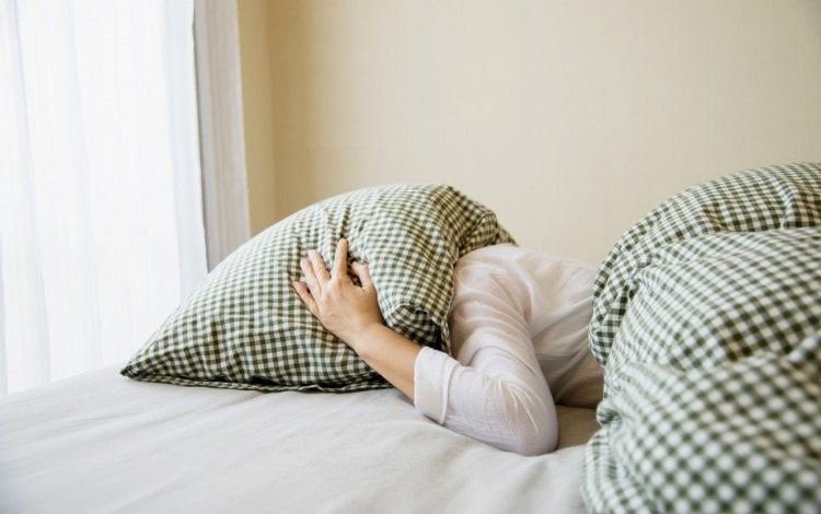 imagen de una mujer con su cabeza bajo la almohada.