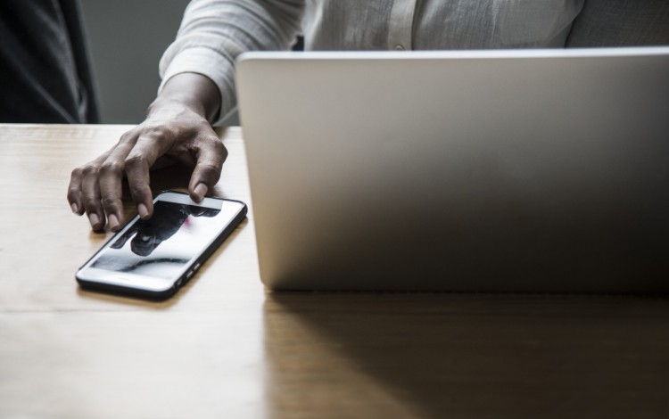 Una mujer en la computadora y usando el teléfono.