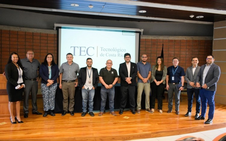 Hombres y mujeres posando en el auditorio, con el logo del TEC de fondo. 