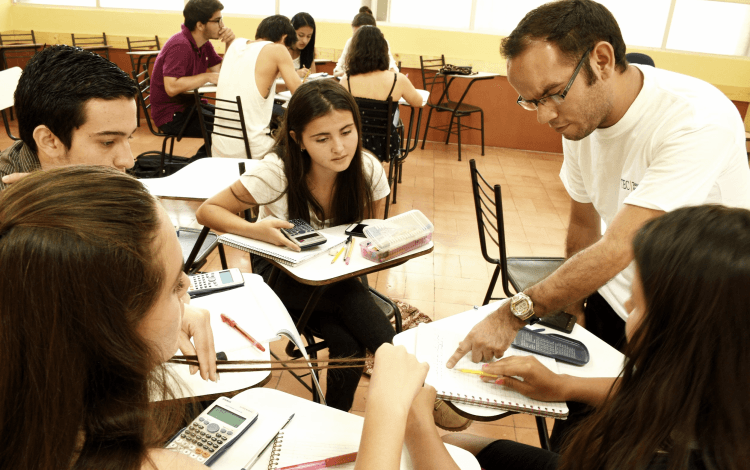 grupo de estudiantes sentados en aula con docente de matemática 