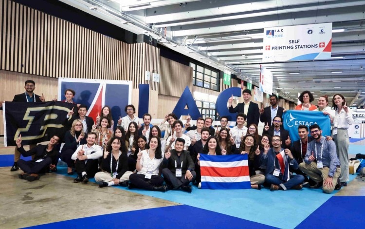 Integrantes de Polaris frente al rótulo de IAC 2022, con la bandera de Costa Rica.