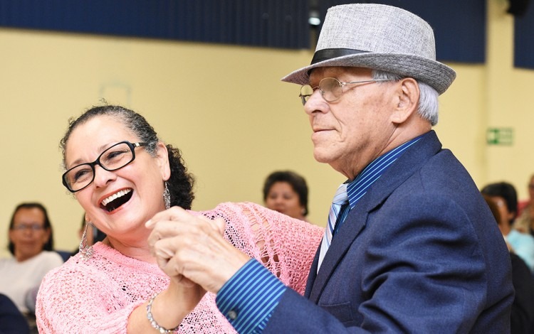 Una pareja de adultos mayores baila tomados de la mano.