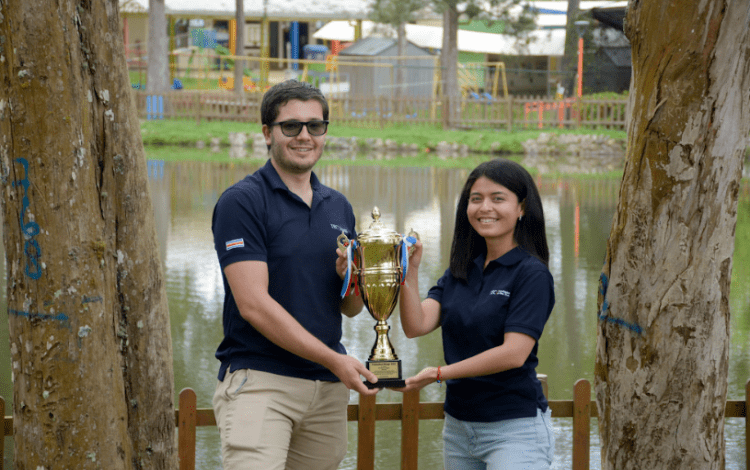 Imagen de dos estudiantes sosteniendo el trofeo