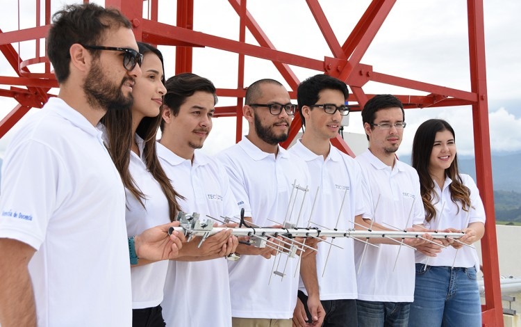 Los estudiantes posan frente a una antena de comunicaciones.