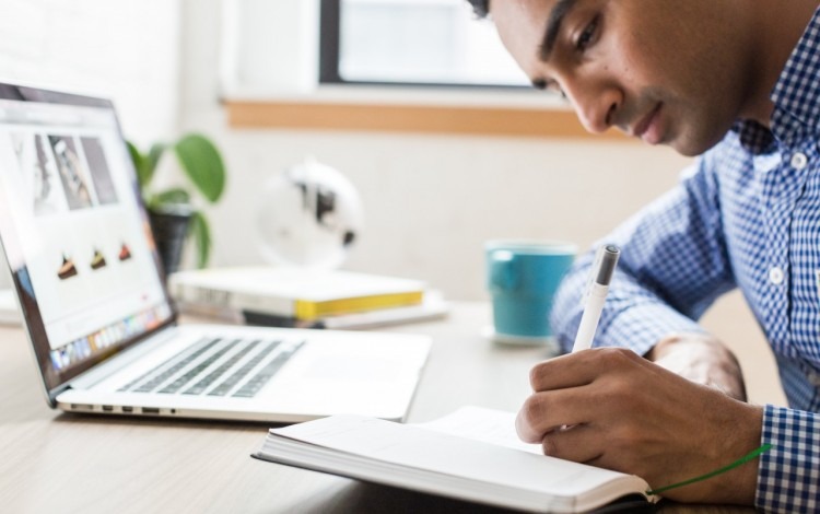 estudiante escribiendo junto a computadora