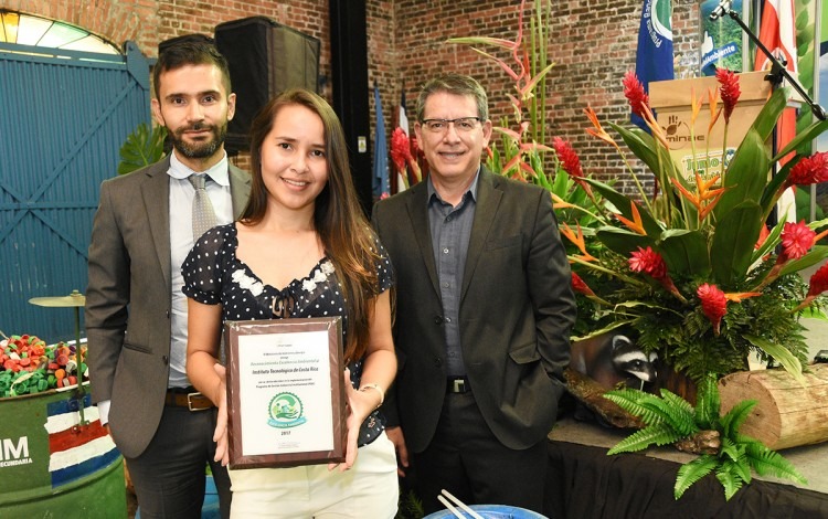 La regente ambiental sostiene el premio, acompañada del rector y el coordinador de la unidad de gestión ambiental.