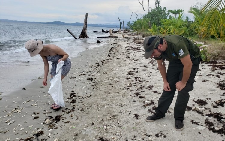 imagen de dos personas juntando residuos de la playa