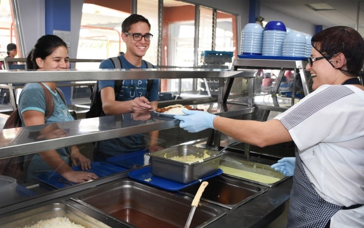 Dos estudiantes esperando que le sirvan almuerzo en el Restaurante Institucional del TEC.