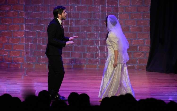 Un hombre y una mujer con ropa de boda en el escenario.