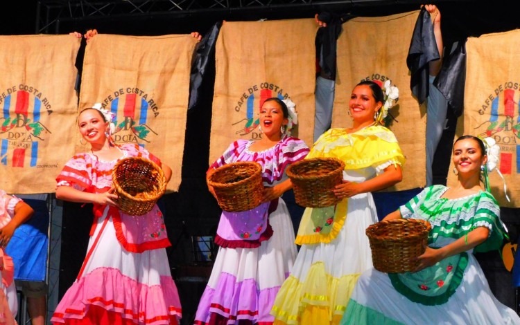 4 bailarinas de Tierra y Cosecha vestidas con traje típico sostienen, cada una, una canasta de recolectar café. 