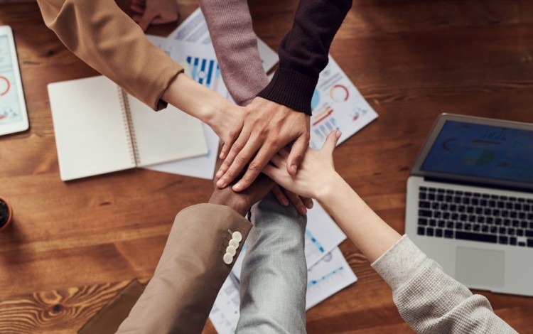 Manos juntas de personas trabajando en equipo.