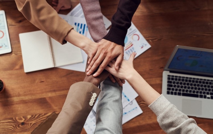 Manos juntas de personas trabajando en equipo. 