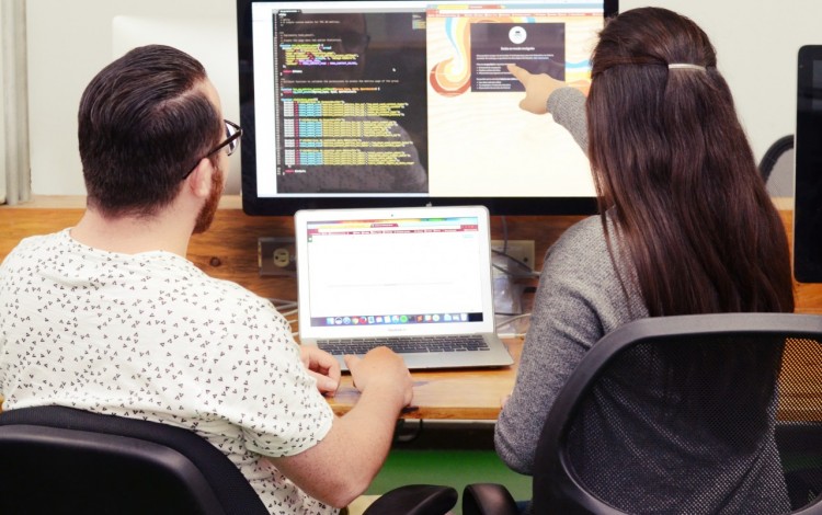 jóvenes señalando una computadora 